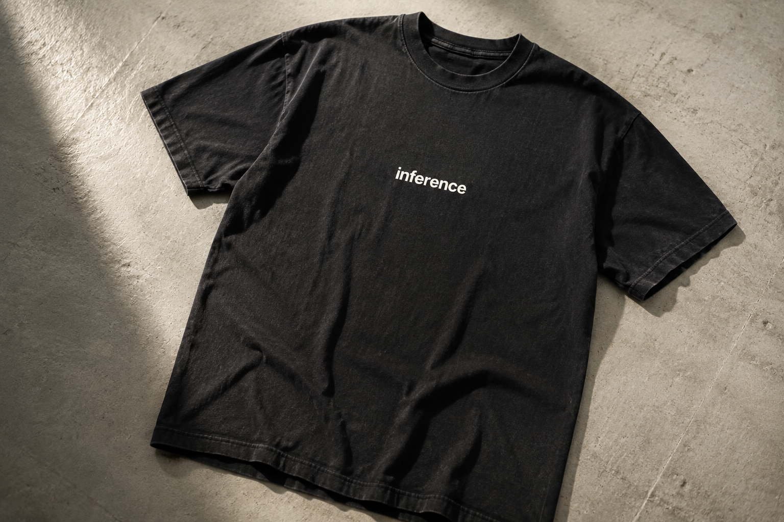 Concept flat lay of a washed black Inference T-shirt on concrete